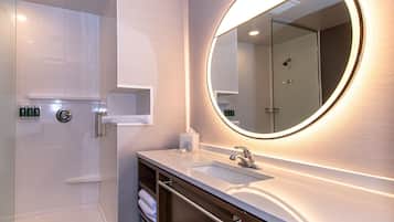 A modern bathroom with a large mirror, a sink, and a shower.