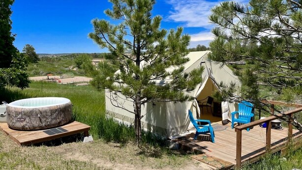 Una tienda de campaña con terraza, jacuzzi y mobiliario exterior.