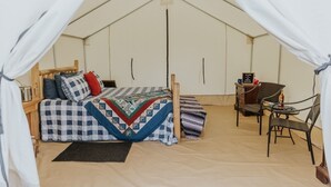Una habitación con carpa, una cama, una silla, una mesita y un reloj en la pared.
