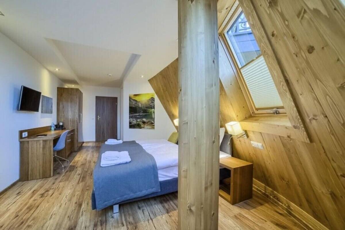 Ein Schlafzimmer mit Bett, Schreibtisch, Stuhl und einem Oberlicht.