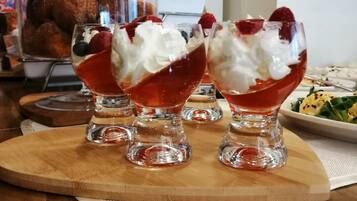 Three dessert glasses with whipped cream and berries on a wooden board.