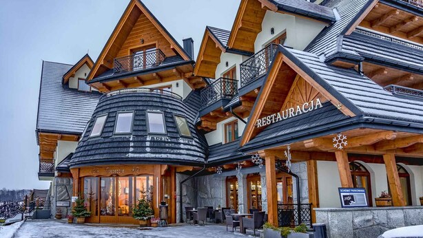 Un bâtiment de style chalet en bois, comprenant un restaurant appelé « RESTAURACJA » et un espace d’accueil.