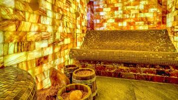 A room with a mosaic wall, a tiled floor, and three wooden barrels.