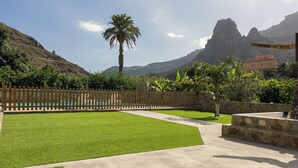 Un espacio exterior cuidado con piscina, valla de madera y muro de piedra.
