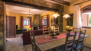 Un comedor con una mesa de madera, sillas y una pared de piedra.