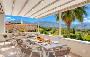 A dining area with a table set for breakfast, overlooking a mountainous landscape.