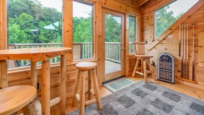 A wooden cabin with large windows, a deck, and a staircase. - FlatBackyard, FirePit, HotTub, Horseshoes, games, 60-game arcade FUN 4 FAMILIES! (Sevierville)