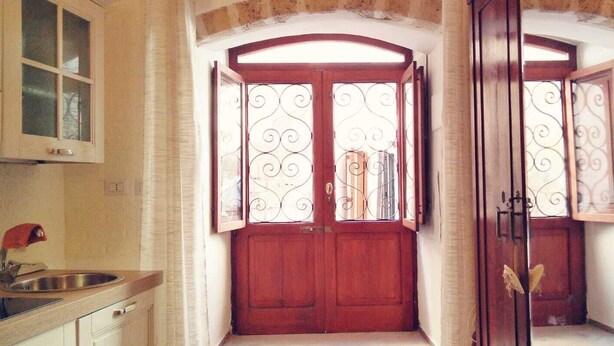 A kitchen with a sink, cabinets, and a double door with decorative ironwork. - Tourist Location Joy's Home (Bari)