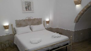 A neatly made bed with white linens and rolled towels, a decorative headboard, and two wall-mounted light fixtures. - Tourist Location Joy's Home (Bari)