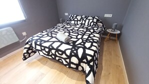 A bedroom with a bed, a bedside table, a lamp, and a window. - Ap1 Valdés de Avilés (Avilés)