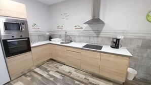 A modern kitchen with wooden cabinets, a built-in oven, a microwave, a sink, and a coffee maker. - Ap1 Valdés de Avilés (Avilés)