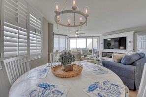 A spacious living room with a round table, a blue sofa, and a television.