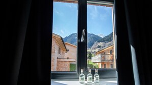 A window with three bottles of The Dos Equis beer on a ledge, overlooking a mountain and buildings.