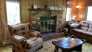 A cozy living room with a brick fireplace, wooden furniture, and a 'Wi-Fi' sign. - 4br 2ba Chalet in Poconos that sleeps 10 (Bushkill)