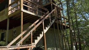 A rustic wooden cabin with a staircase leading to a deck, surrounded by trees. - 4br 2ba Chalet in Poconos that sleeps 10 (Bushkill)