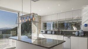 Cozinha moderna com uma ilha grande, eletrodomésticos embutidos e vista para as montanhas.