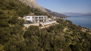 Uma casa moderna de dois andares com teto plano, janelas amplas e uma varanda com vista para um lago.