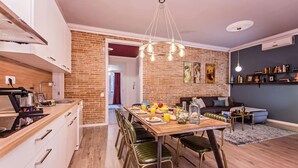 Une cuisine moderne avec un coin repas, comprenant un mur en briques, un lustre et une table à manger dressée pour six personnes.