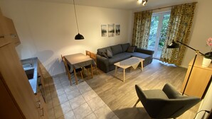 A living room with a sofa, a dining table with chairs, a small coffee table, and a modern lamp.