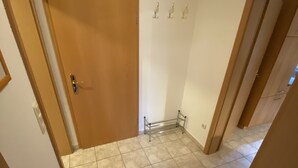 A hallway with a wooden door, a metal rack, and tiled flooring.