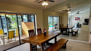 Uma sala de jantar ampla, com mesa e bancos de madeira, janelas grandes e vista para o exterior.