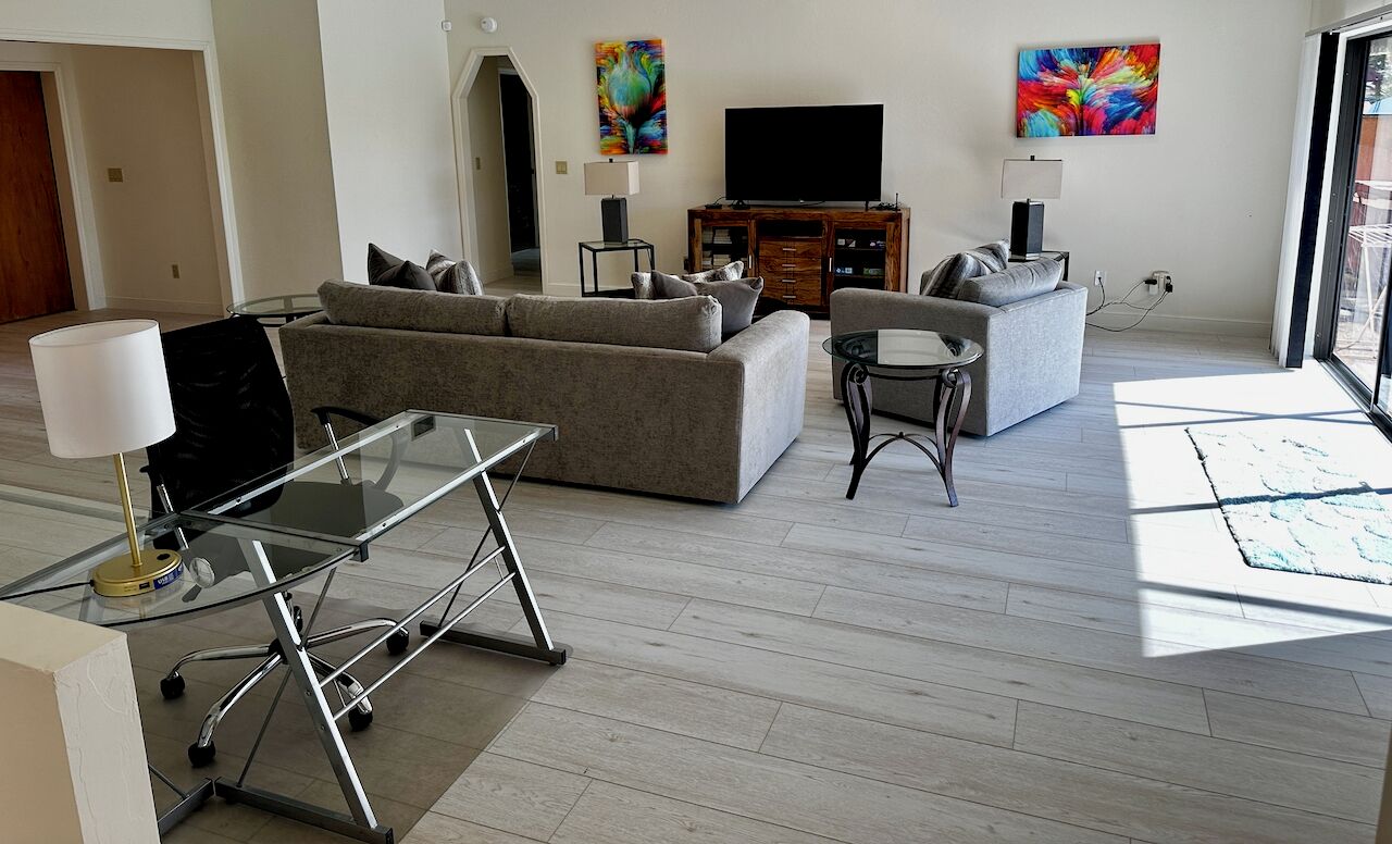 Ein modernes Wohnzimmer mit einer Couch, einem Glastisch und einem Fernseher.