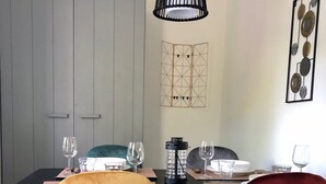 A dining area with a table set for four, featuring two chairs with contrasting upholstery, a modern pendant light, and a decorative wall piece. - Compact, trendy furnished, vacation bungalow. Enclosed garden. Pets welcome! (Bruinisse)