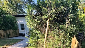 A wooden fence in a backyard with a pathway leading to a house. - Compact, trendy furnished, vacation bungalow. Enclosed garden. Pets welcome! (Bruinisse)