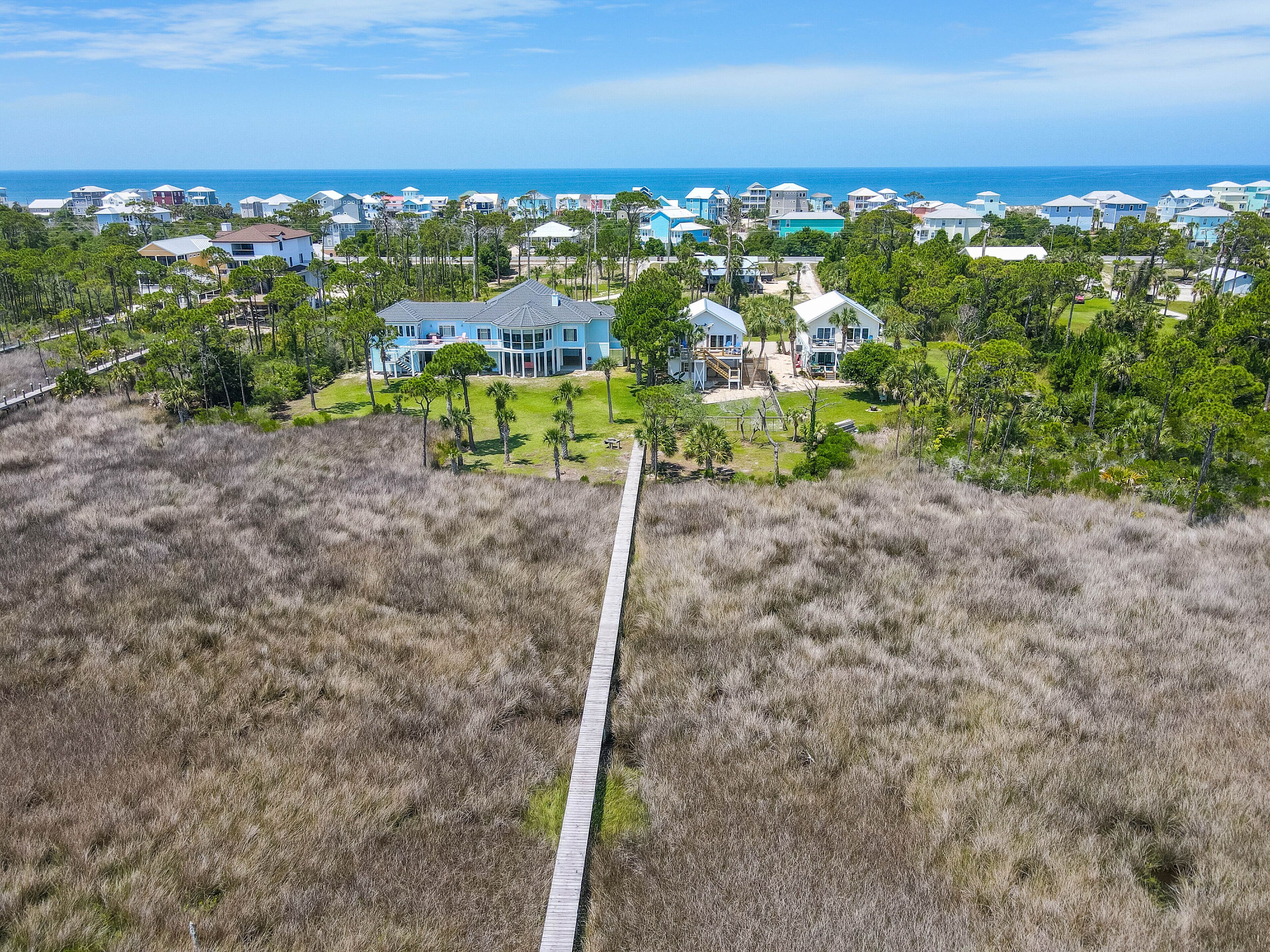 A coastal residential area with houses, a wooden pathway, and a view of the ocean.