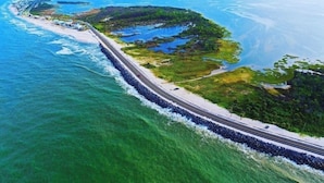 Luftaufnahme einer Küstenstraße mit Strand und Vegetation.