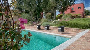 Piscina nítida amb un marc de rajola, envoltada de mobiliari exterior i vegetació abundant.