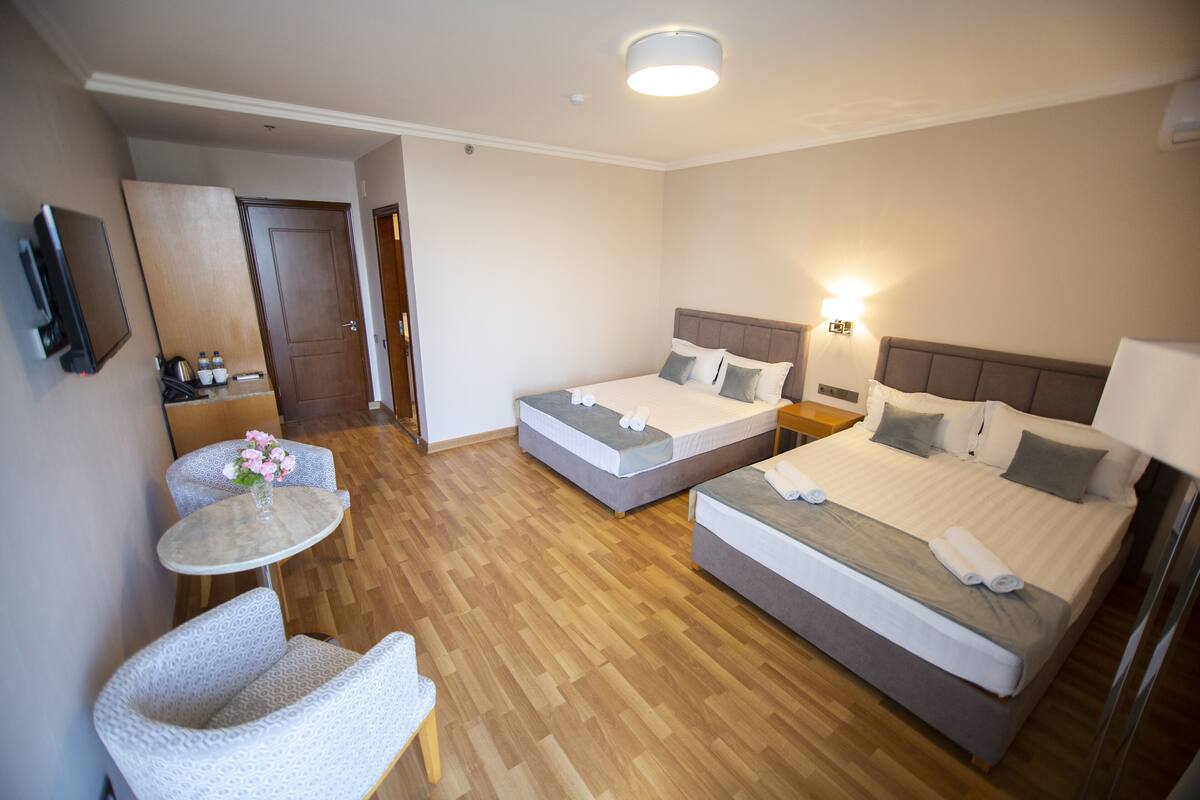Une chambre d’hôtel avec deux lits, une petite table et une chaise, un téléviseur et un plancher en bois.