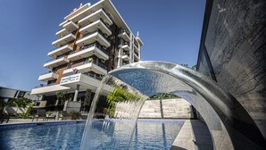 Een modern hotel met een zwembad en een fontein.