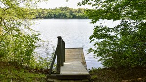 A wooden dock leading to a calm lake surrounded by trees.