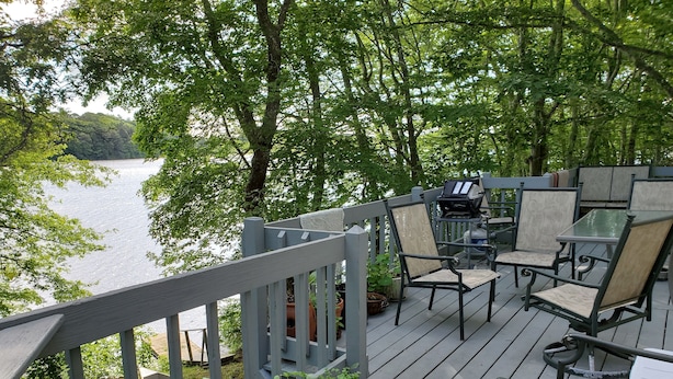 A deck with outdoor furniture, potted plants, and a view of a lake.