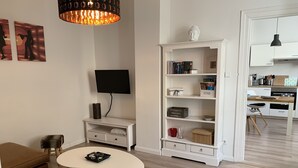 Ein modernes Wohnzimmer mit einem weißen Sofa, einem Couchtisch, einem Bücherregal und einem Fernseher.