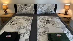 Ein Doppelbett mit Blumenmuster, zwei Nachttische mit Lampen und eine kleine Schublade.