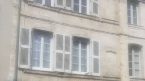A building with large white shutters, a visible door, and a small window. - Nice studio (La Rochelle)