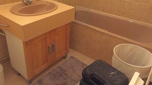 A bathroom with a sink, wooden cabinet, and a bathtub. - Nice studio (La Rochelle)