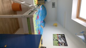 Un dormitorio infantil con literas, un escritorio y una ventana.
