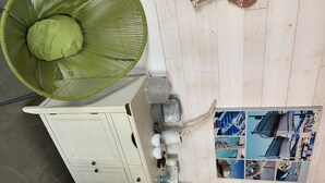 Una habitación con un ventilador verde, un armario blanco y una pared con fotografías.