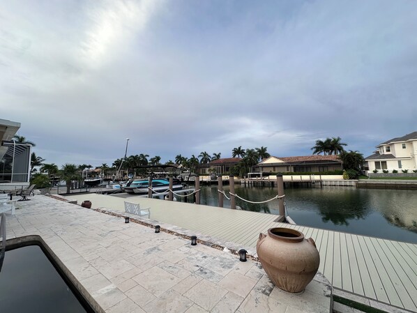 A marina with docked boats, a large ceramic pot, and residential buildings in the background.