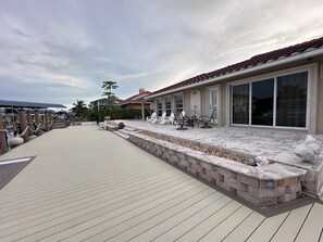 A covered outdoor deck with stone steps and a fire pit, overlooking a body of water. - PELICAN  PARADISE🌴 (Marco Island)