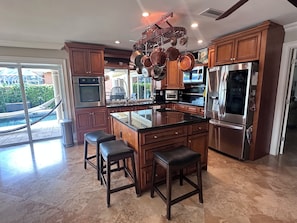 A modern kitchen with a central island, stainless steel appliances, and wooden cabinetry.