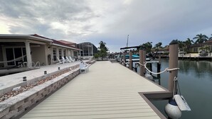 Ein Ufergrundstück mit Holzsteg, der zu einem Yachthafen führt, mit überdachter Sitzgelegenheit und Schwimmbad.