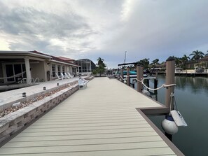 A waterfront property with a wooden dock leading to a marina, featuring a covered seating area and a pool. - PELICAN  PARADISE🌴 (Marco Island)