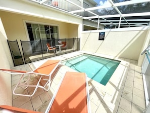 A pool area with lounge chairs and a glass-enclosed balcony.