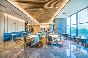 A modern restaurant interior with a variety of seating options, including booths and tables, and a large window providing a view of the city. - Holiday Inn Express Foshan Beijiao by IHG (Foshan)