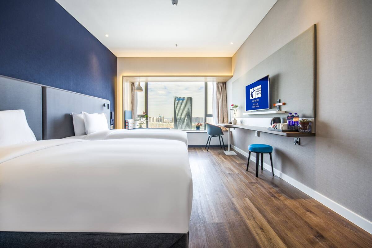 A modern hotel room with a large bed, a desk, and a TV.