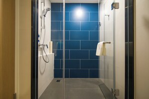 A glass-enclosed shower area with a blue-tiled wall, a white towel rack, and a glass door. - Holiday Inn Express Foshan Beijiao by IHG (Foshan)